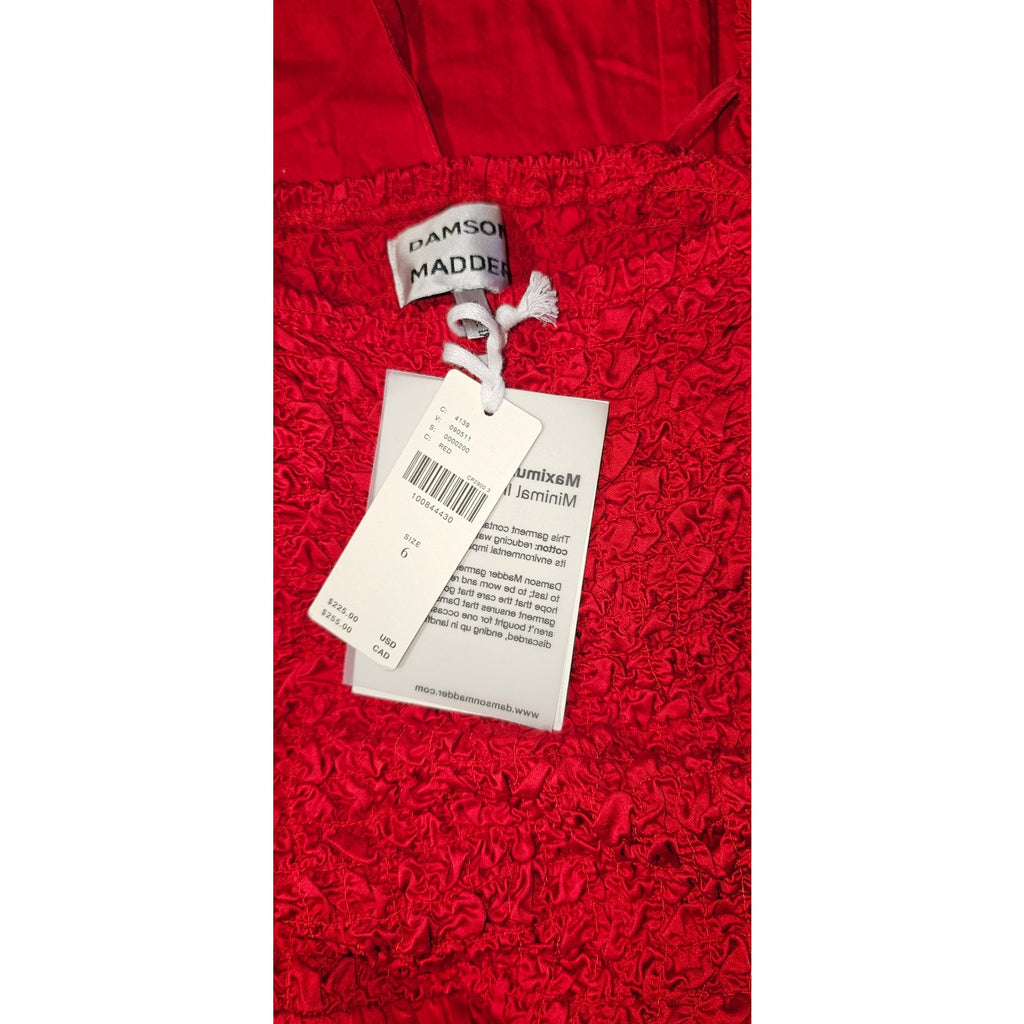 Red textured fabric with hanging garment tags, including barcode and brand labels.