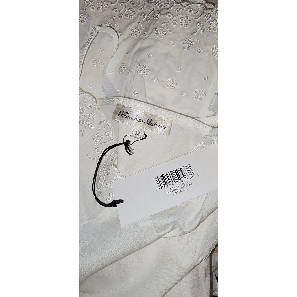White poplin mini dress label close-up with barcode tag on fabric