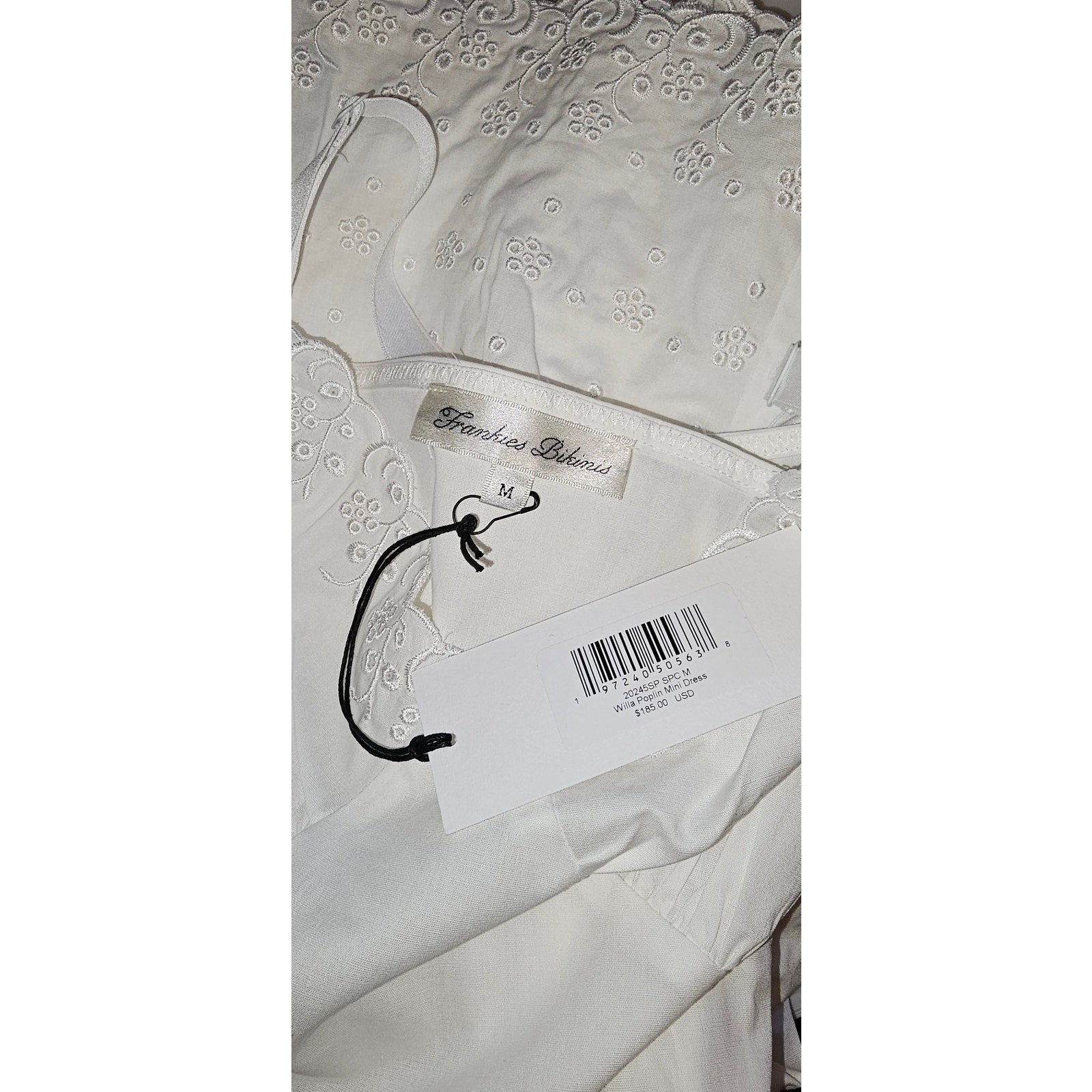 White poplin mini dress label close-up with barcode tag on fabric