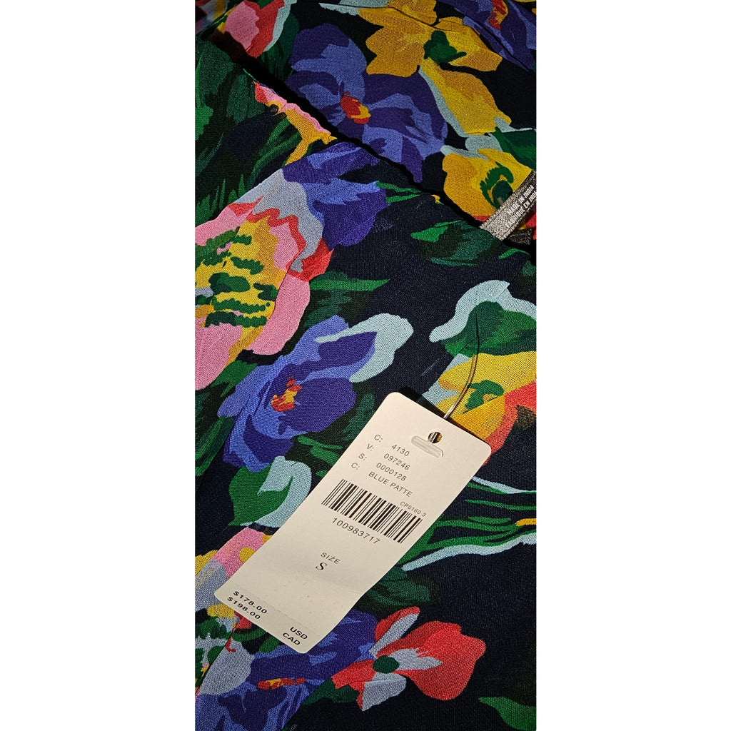 Floral printed fabric swatch with care tags attached, on dark blue background