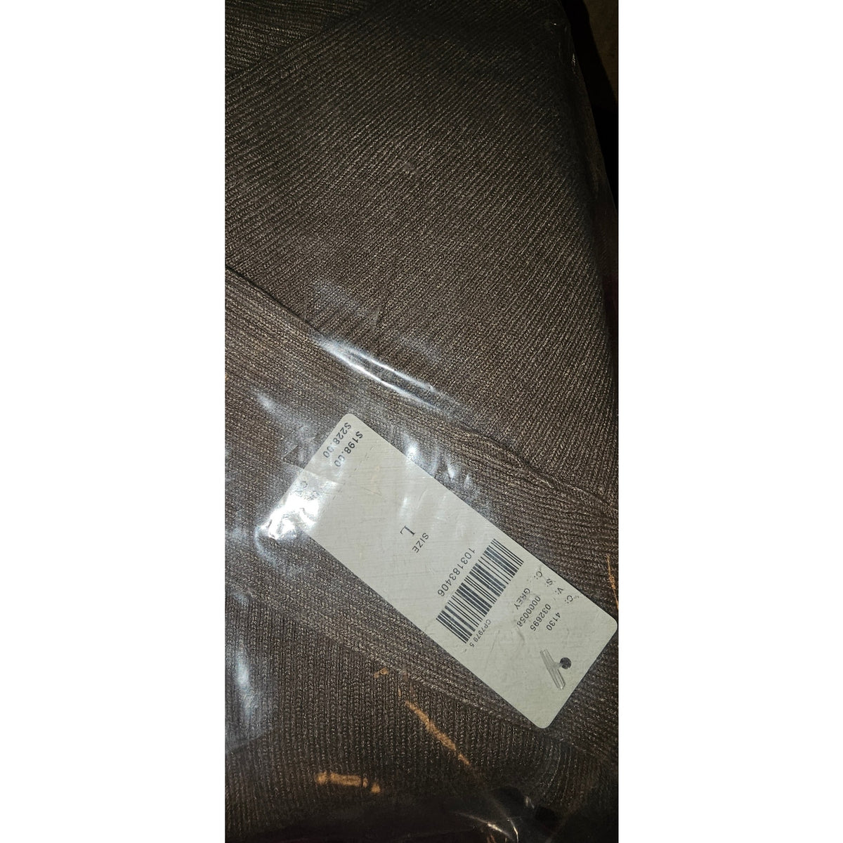 Knitted sweater dress fabric close-up with care label tag, gray-brown