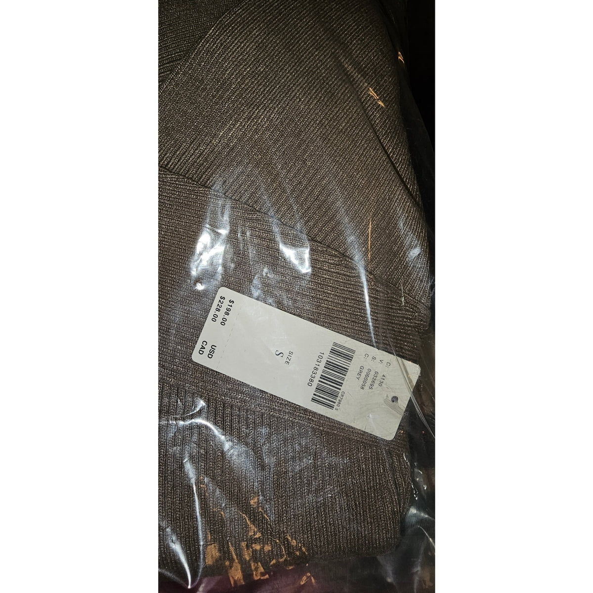 Gray knit sweater fabric close-up with barcode label in clear plastic