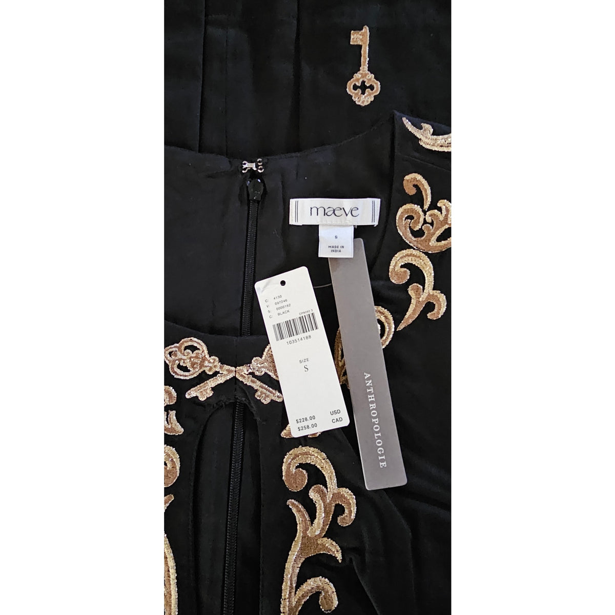Black mini dress close-up with gold embroidery and attached retail tags