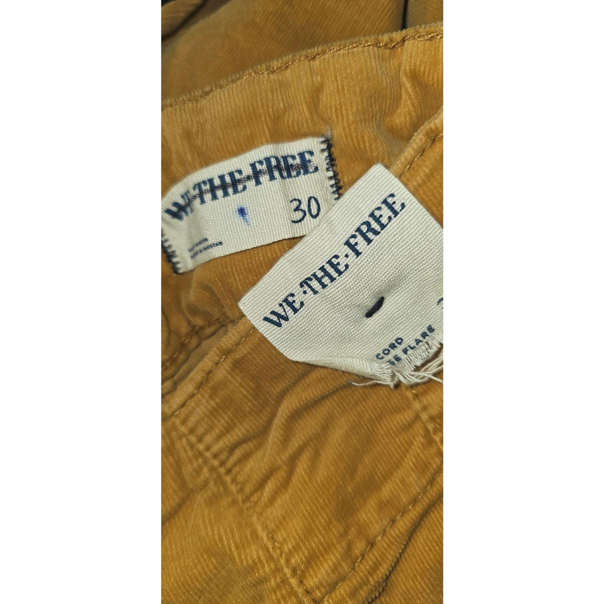 Mustard corduroy jeans label with size 30 and With the Free tag