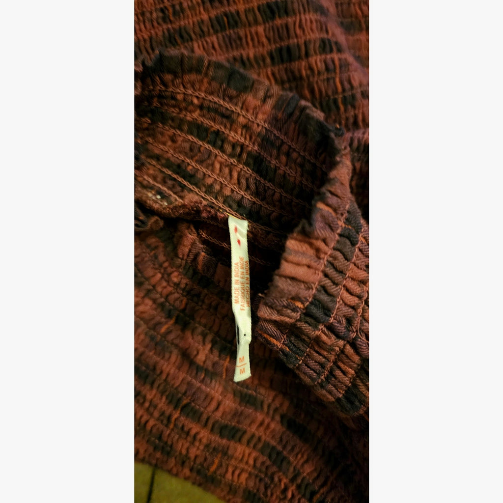 Close-up of magenta plaid fabric with gathered trim and size label at seam