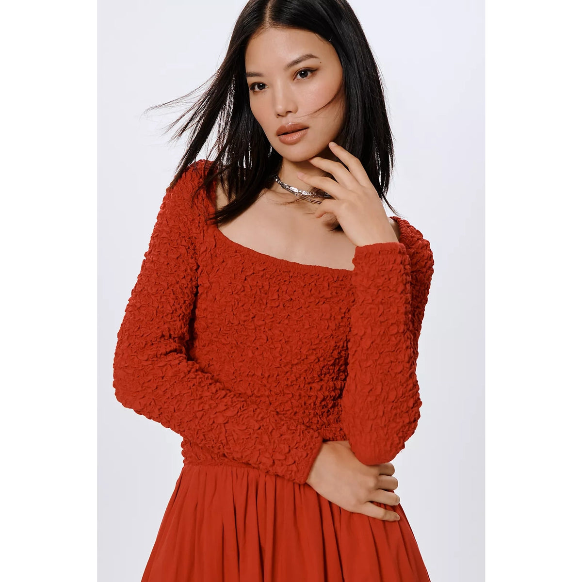 Rust red long-sleeve smocked bodice and scoop neck midi dress, close-up view.