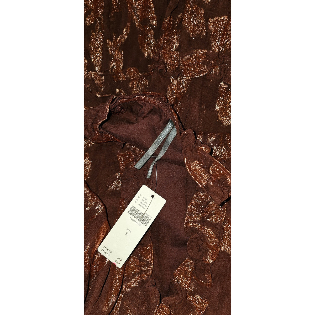 Close-up of dark plum-brown metallic print mini dress with hanging size tag