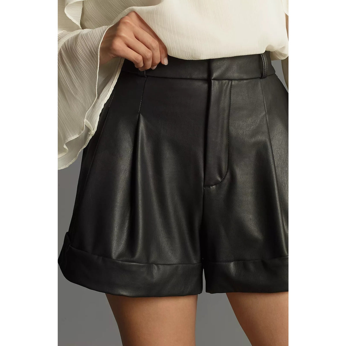 Black faux leather shorts with pleated front panel and structured cuffed hem